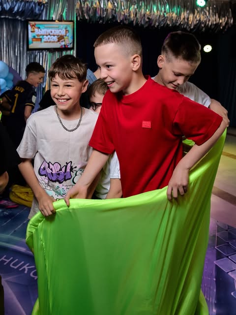Дети играют с игровым парашютом на выпускном